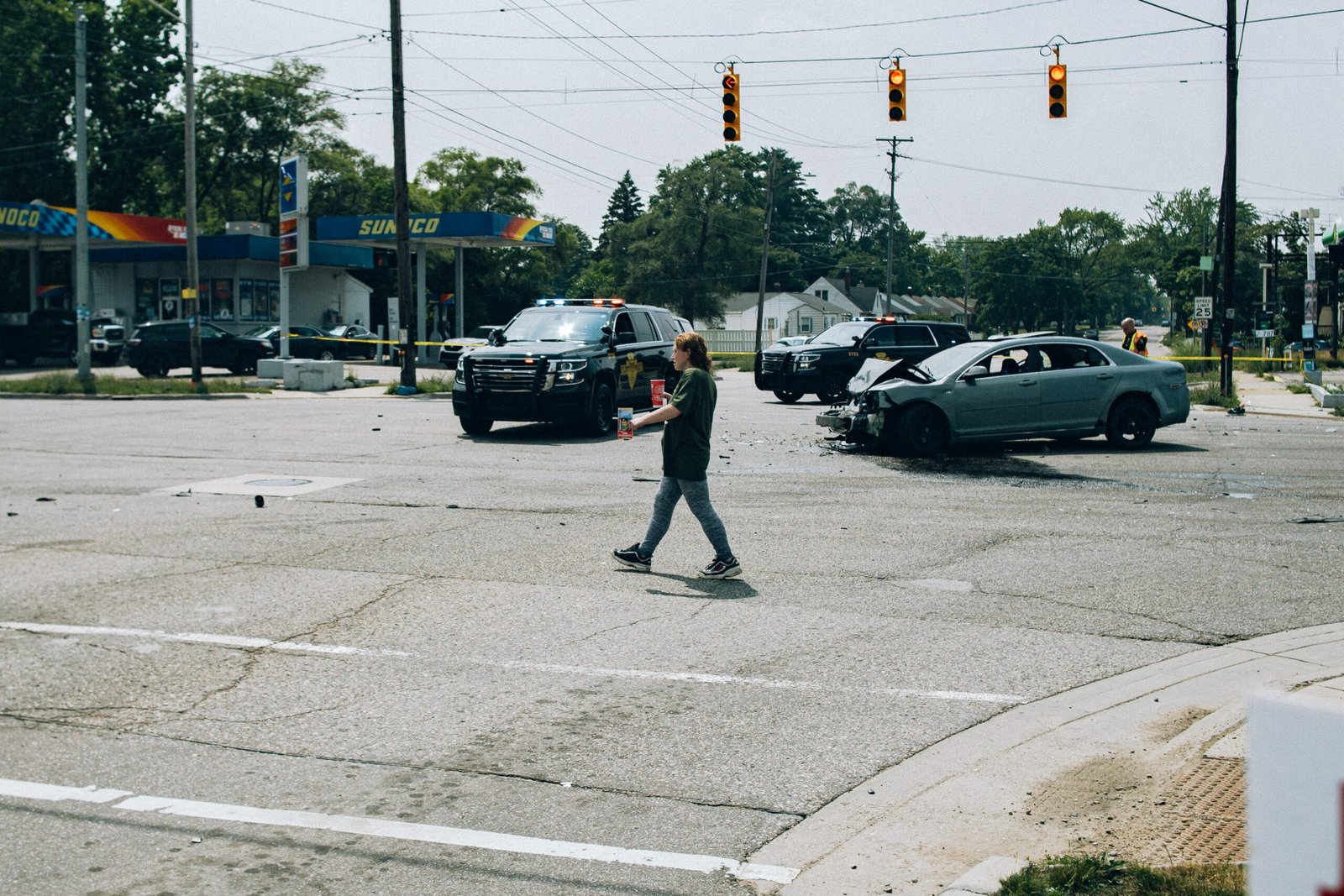 Pedestrian walking near vehicles and police activity at a traffic collision