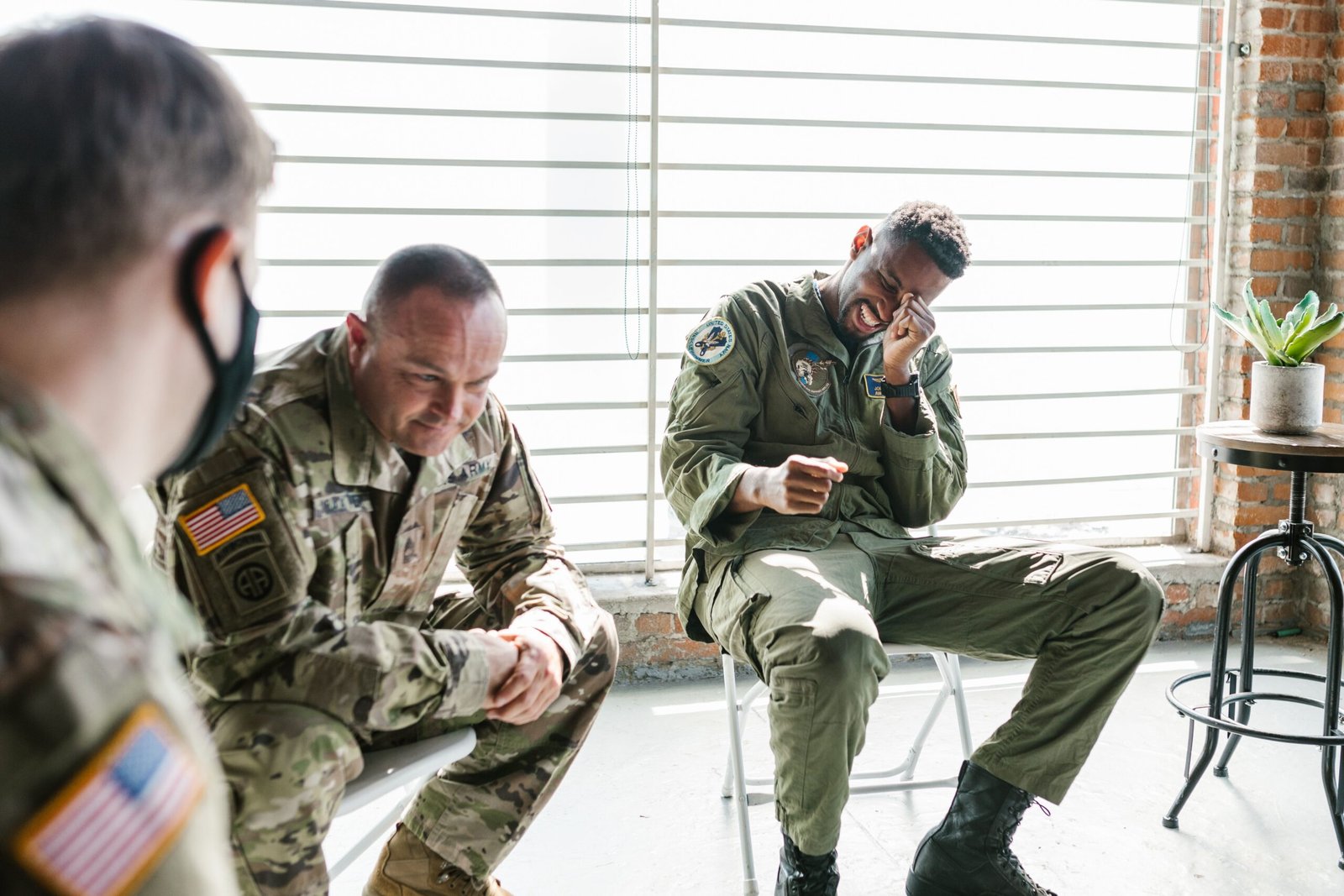 Three soldiers in military uniform sitting in a circle during a group support session.