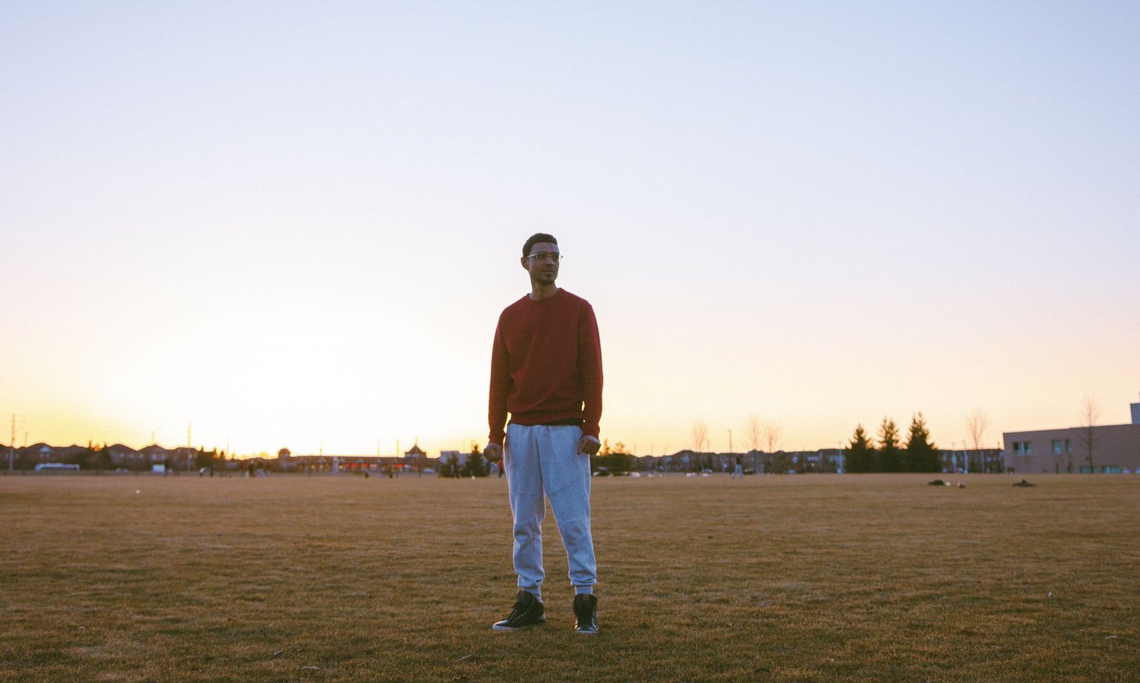 A man standing alone in an open field at first light.