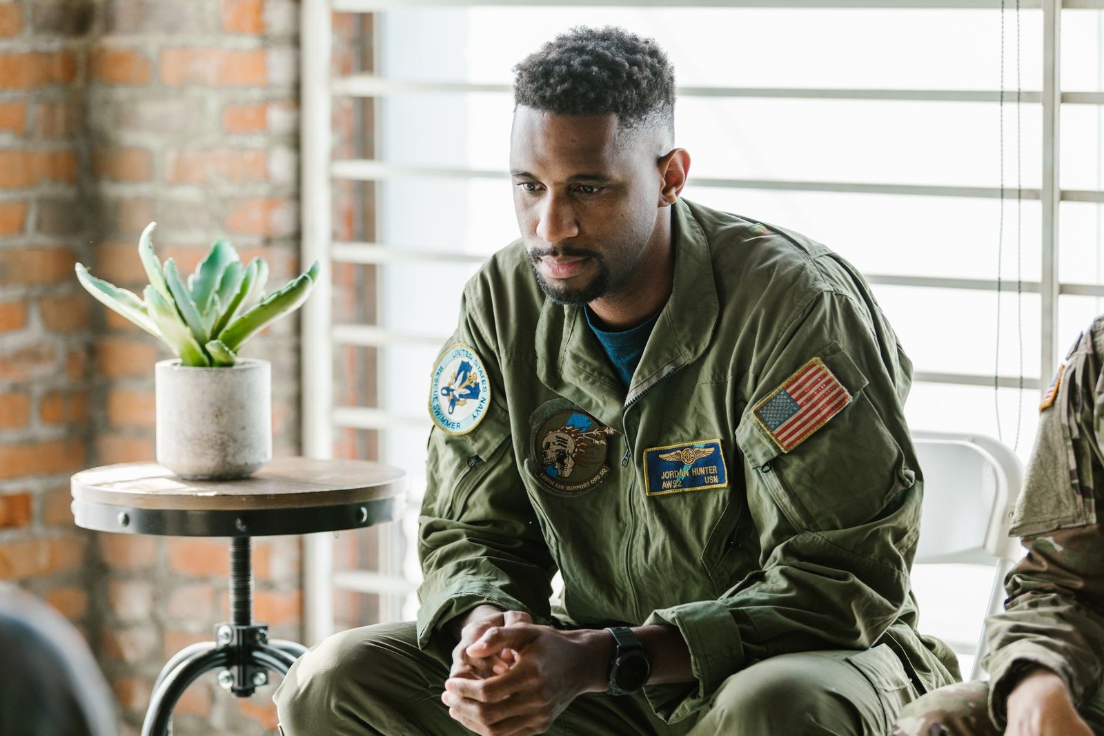 A service member sitting quietly by a window, lost in thought.